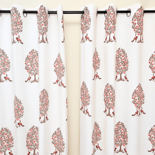 Block printed curtain with repeated pink peacock under tree design, hanging on black eyelet rod