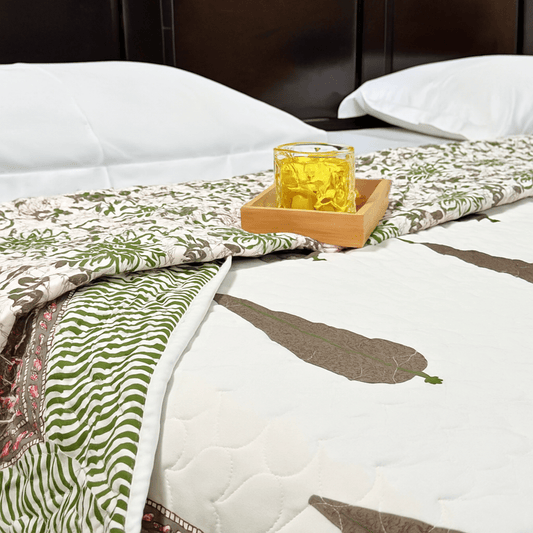Cozy cotton quilt with reversible green and floral side, styled with wooden tray and yellow glass