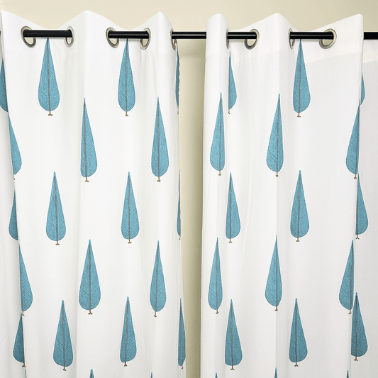 Minimalist cotton curtain with blue tree motif hanging on a black eyelet rod