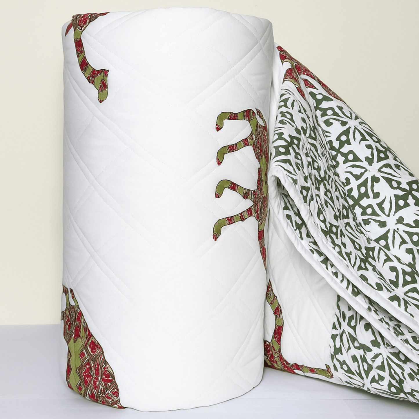 Rolled cotton quilt with traditional camel block print in red and green, showcasing fine quilting and border design.