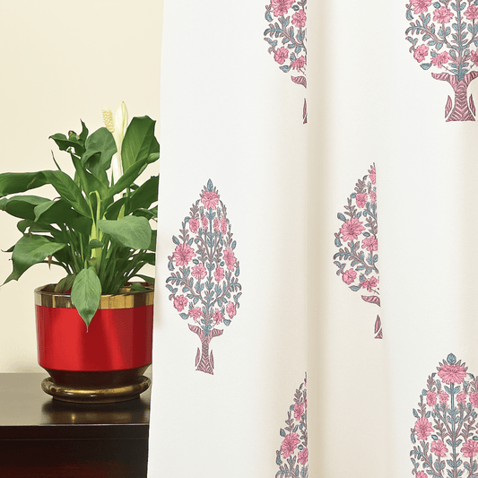 Cotton curtain with pink tree block print, styled besides green indoor plant