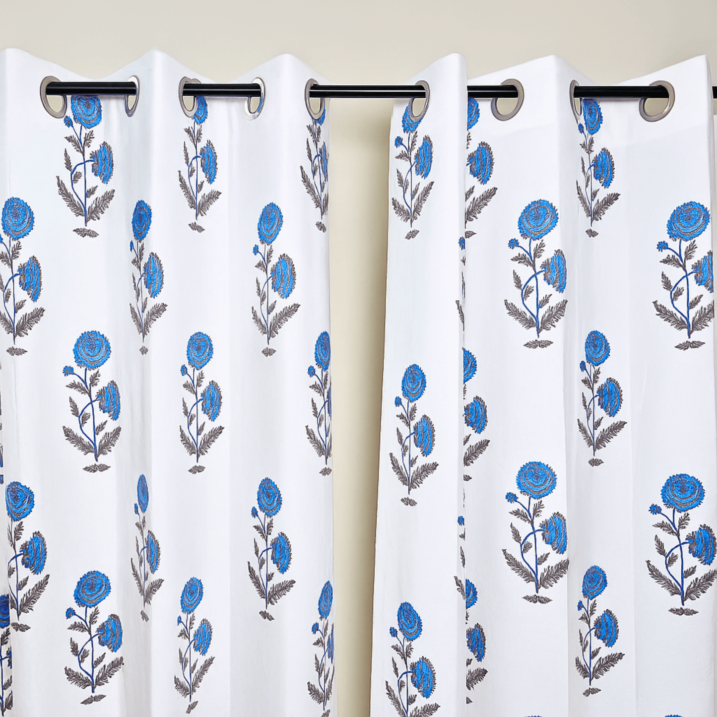Jaipuri block print curtains with blue flowers hanging on black curtain rod

