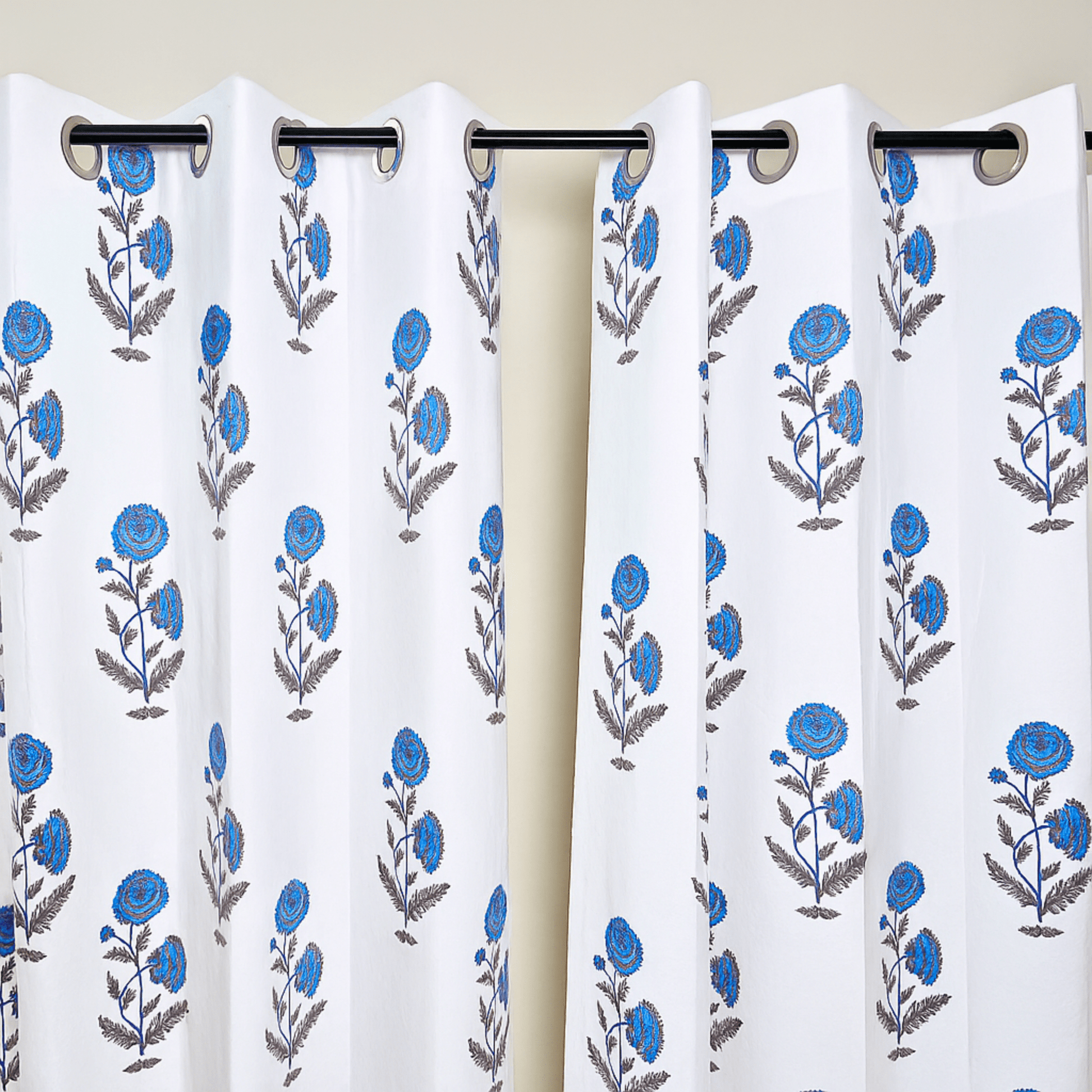 Jaipuri block print curtains with blue flowers hanging on black curtain rod

