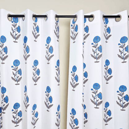 Jaipuri block print curtains with blue flowers hanging on black curtain rod

