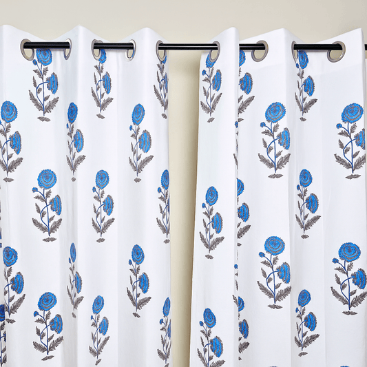Jaipuri block print curtains with blue flowers hanging on black curtain rod

