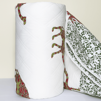 Rolled cotton quilt with traditional camel block print in red and green, showcasing fine quilting and border design.