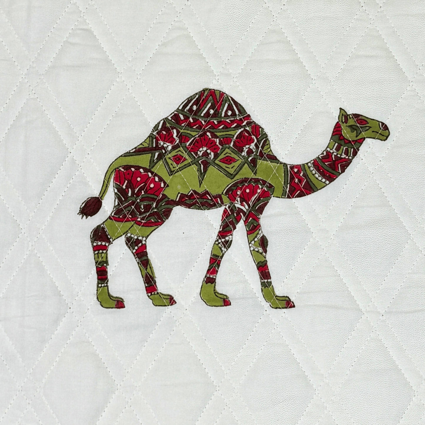 Detailed view of a red and green handprinted camel block on white quilted cotton fabric.
