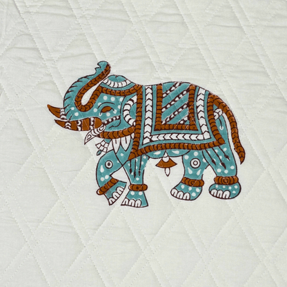 Close-up of a single elephant block print on white quilted fabric, handprinted in earthy tones with fine detailing.

