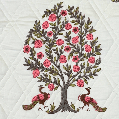 Detailed view of handprinted quilt featuring twin peacocks under a pomegranate tree with pink floral accents