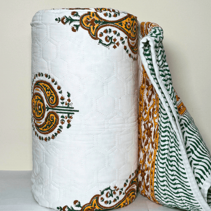 Rolled Jaipuri quilt with detailed paisley block prints and floral borders, showing both the printed front and striped reverse side.